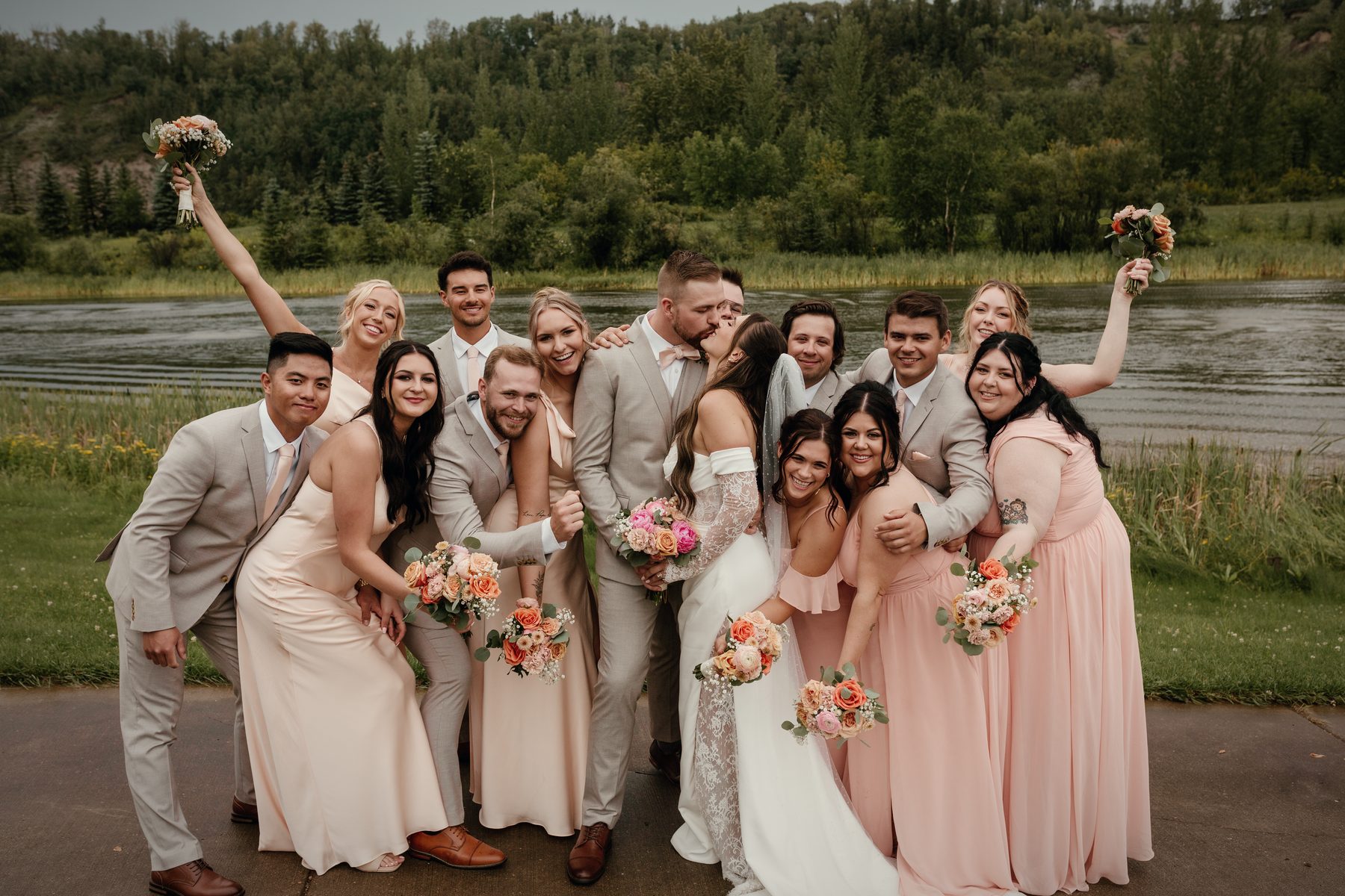 The wedding party crowded together at the lake, laughing, bouquets in the air
