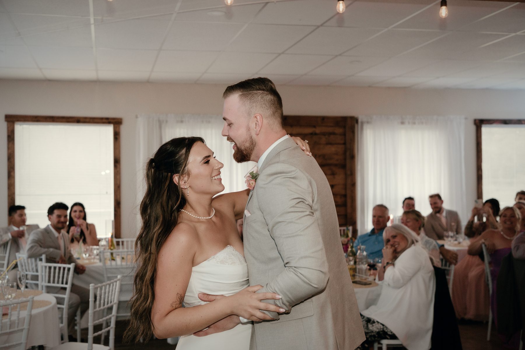 The first dance, the couple smiling at each other as guests look on