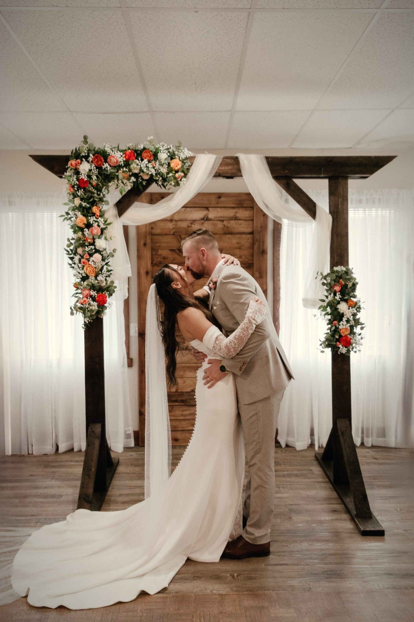 A kiss beneath the timber arch in the hall, the bride's veil trailing across the floor
