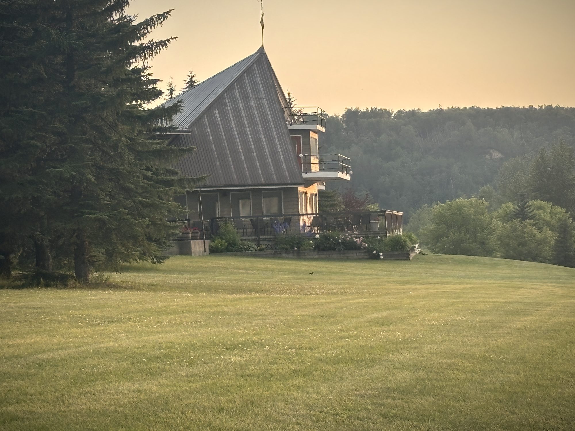 The hall in the last gold light of the evening, the lawn running down toward the water