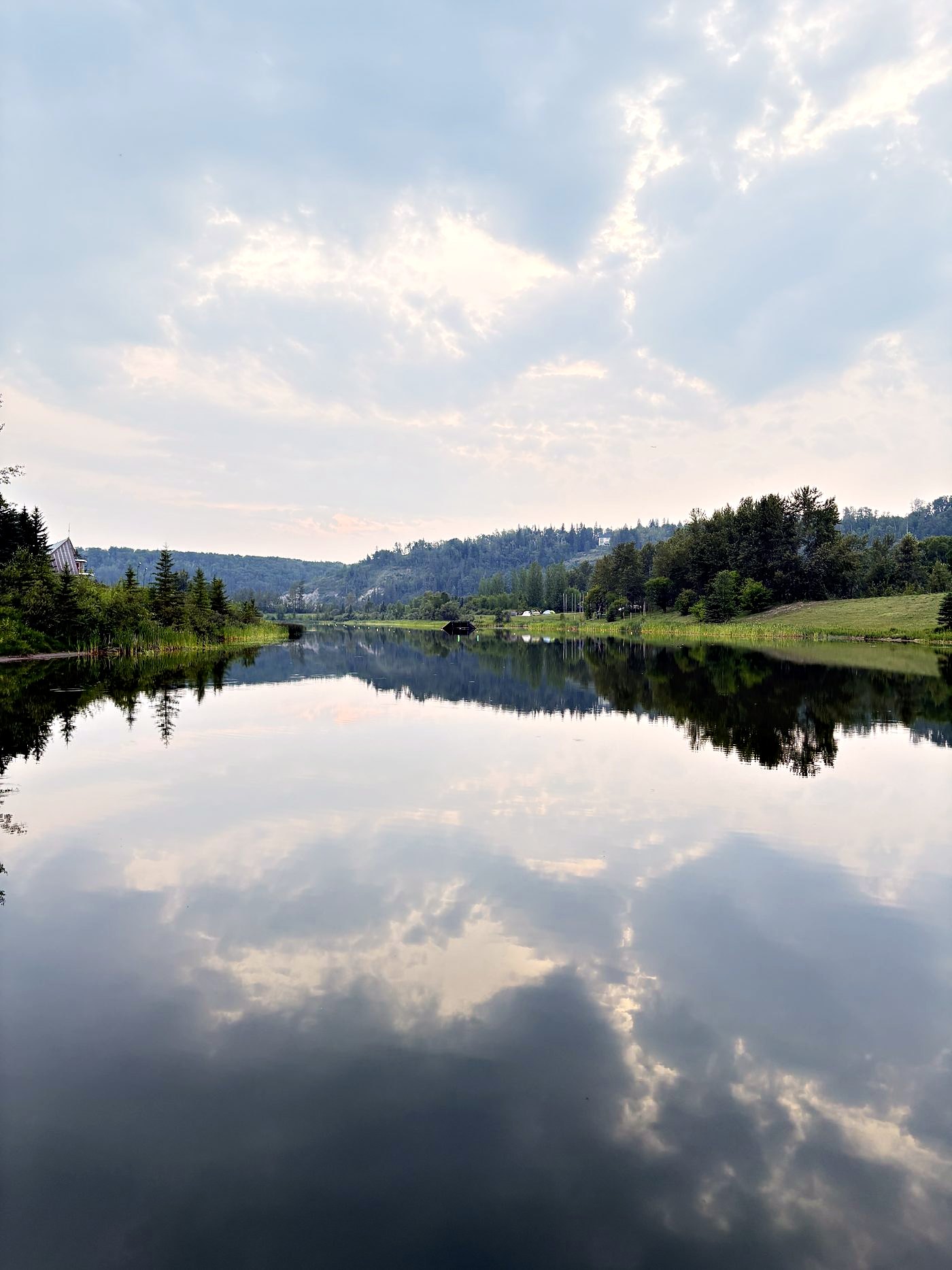 The lake holding the far bank and the whole sky at once, unbroken from one shore to the other